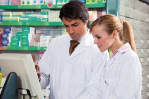 portrait of two pharmacists looking at computer monitor